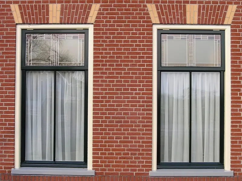 Twee ramen met glas-in-loodbovenlichten en hanenkammen in het metselwerk, notariswoning Spanbroek