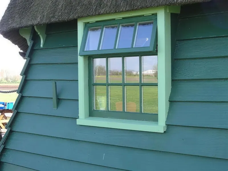 Groen klapraam in het potdekselwerk onder het riet van een molen bij Obdam