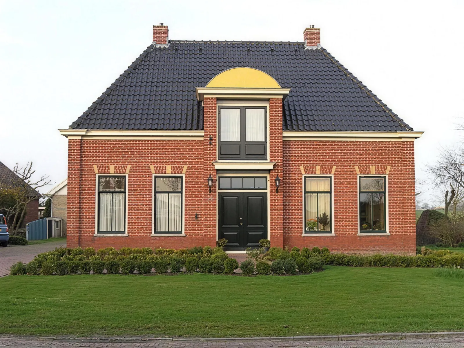 Notariswoning in Spanbroek van rode baksteen met donker pannendak, twee schoorstenen en middenpartij