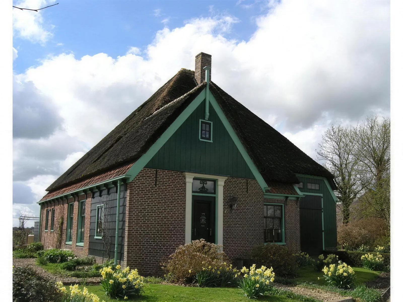 Stolpboerderij in Sijbekarspel met rieten kap, groene topgevel en voorgevel van rode baksteen