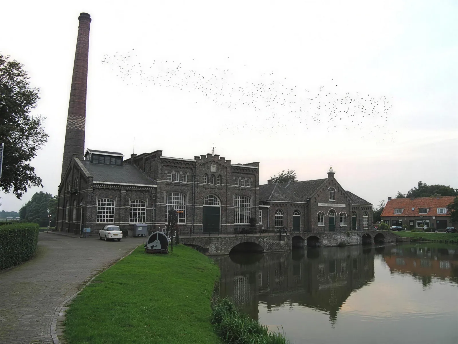 Stoomgemaal in Medemblik aan het water met hoge schoorsteen en bakstenen gebouwen met boogramen