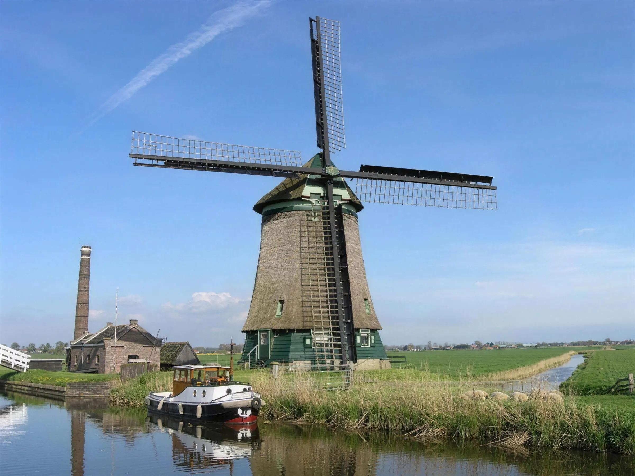 Gerestaureerde poldermolen met rieten lijf en groen houtwerk aan het water bij Obdam