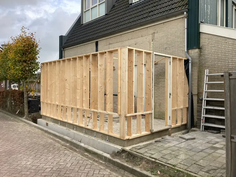 Houten skelet van de aanbouw op een betonnen fundering naast de woning in Sijbekarspel