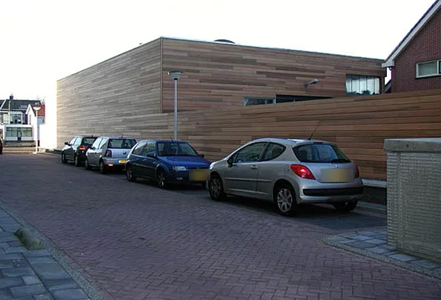 Zijgevel van het bedrijfspand in Zaandam bekleed met Red Cedar, geparkeerde auto's ervoor