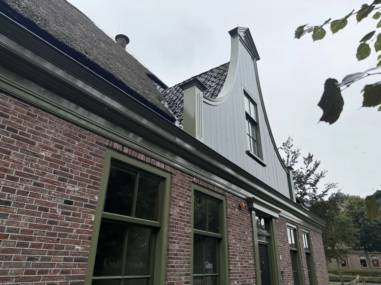 Stolpboerderij in Opmeer met rieten kap, gebogen topgevel en bakstenen voorgevel