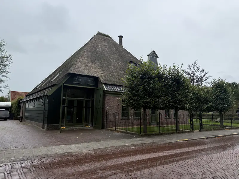 Schuurdeel van de stolpboerderij in Opmeer met donkergroene houten gevel en groene deeldeuren