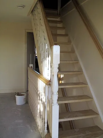 Witte trap met gedraaide spijlen en houten treden in de hal, notariswoning in Spanbroek