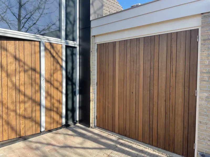 Houten dubbele deuren in de glazen pui en de houten garagedeur ernaast, woning in Hoorn