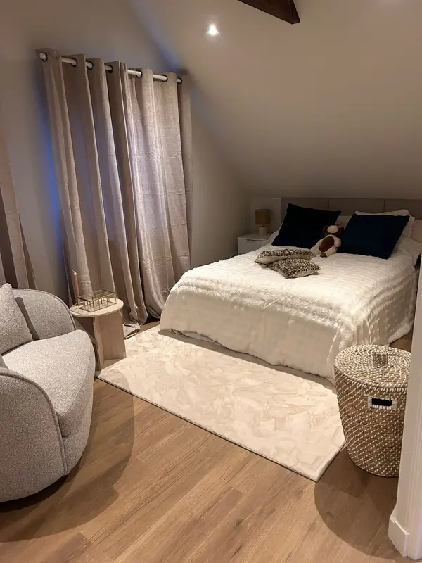 Bed onder de schuine kap van de slaapkamer, inbouwspot en lichte houten vloer