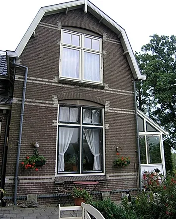 Topgevel met gebogen witte windveren, lichte speklagen en grote ramen, stoomgemaal in Medemblik