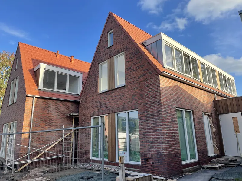 Zijgevels van de twee woonhuizen in Oosthuizen met dakkapel, lange dakkapel en houten delen tussen de ramen