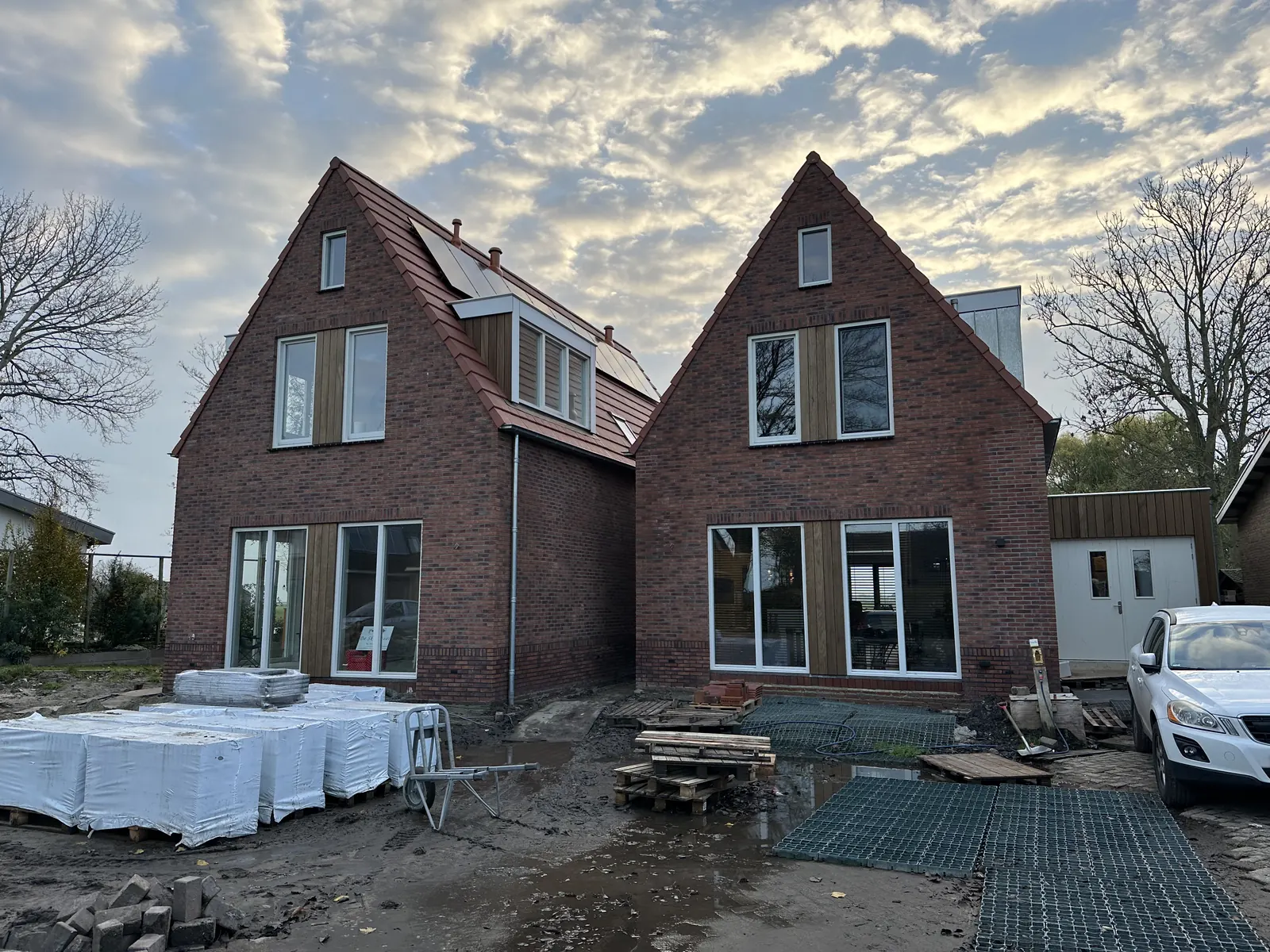 Twee woonhuizen in Oosthuizen van roodbruine baksteen met steile pannendaken en witte kozijnen, kort voor oplevering