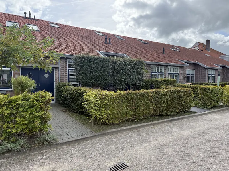 Voordeuren en ramen achter hagen, voormalig verenigingsgebouw in Hoogwoud