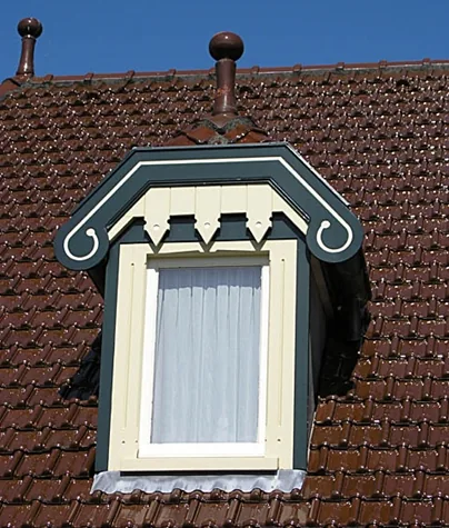 Dakkapel met groene krullen, crèmekleurige getande lijst en sierknoppen op het pannendak, Spanbroek