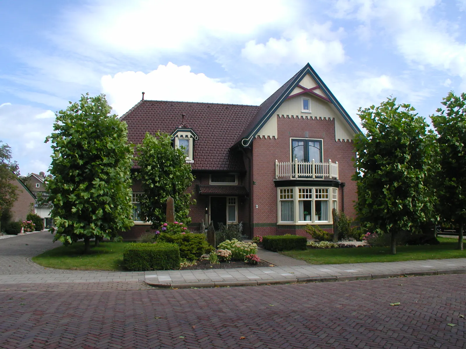 Vrijstaande villa in Spanbroek van rode baksteen met crèmekleurige geveltop, erker met balkon en dakkapel