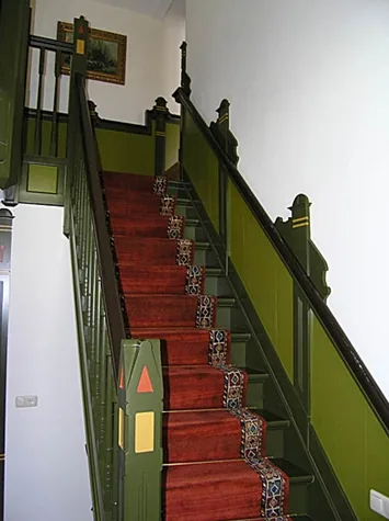 Groen geschilderde trap met rode loper, spijlen en houten lambrisering, villa in Spanbroek