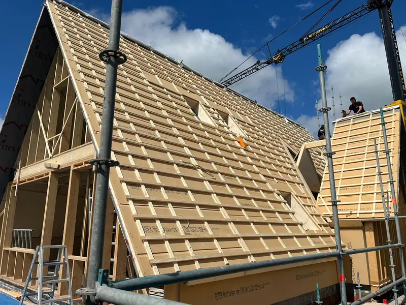 Dakbeschot en panlatten op de kap van het woonhuis in Obdam tijdens de bouw, met kraan op de achtergrond