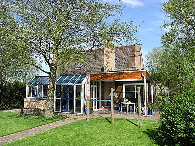 Achterzijde van het woonhuis in Langedijk met houten aanbouw, overdekt terras en glazen serre