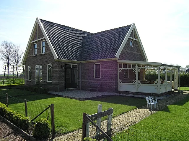 Achterzijde van het woonhuis in Ursem met grasveld en houten veranda aan de zijkant