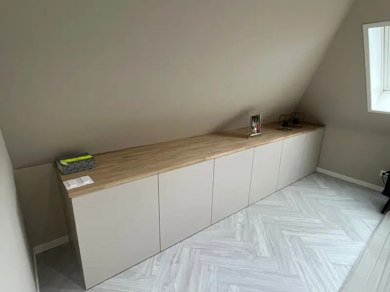 Lage kastenwand met houten blad onder de schuine kap van een zolderkamer in Spanbroek